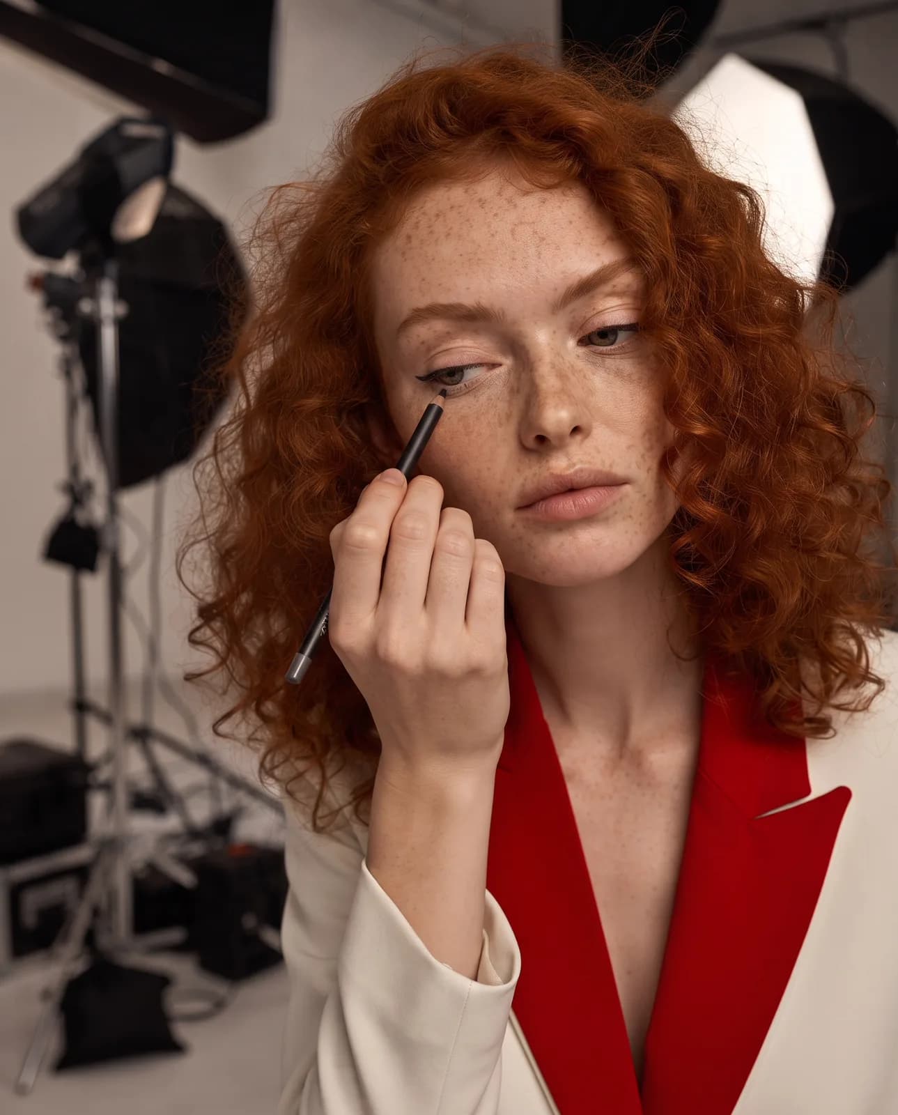 Yapay zekâ ile üretilmiş marka yüzü: stüdyoda eyeliner uygulayan kızıl saçlı model